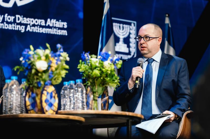 Zvika Klein speaking into a microphone while moderating a panel at the Generation of Truth conference in Jerusalem